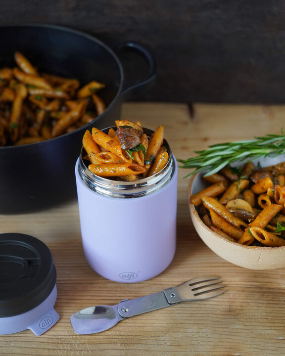 One-Pot Penne Rigate mit Pilzen in Rosmarin-Thymian-Sahnesoße im lilafarbenen alfi Food Mug, servierfertig zum Mitnehmen – daneben ein Topf, frische Kräuter und eine Portion Pasta in einem tiefen Teller